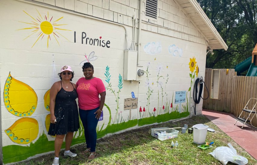Bernadette Cipriani-Major and Highland Christian Academy's Director Rosie Bush standing at the iPromise wall with the freshly-painted mural.