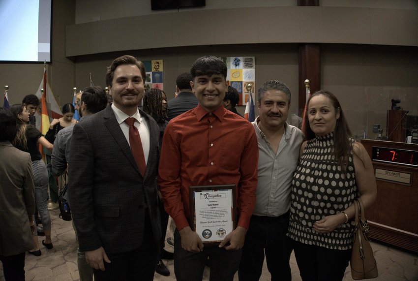 Rojas stands with Commissioner Moore’s aide Alexander Quinones (left) and Luis’ parents (right) at the celebration.