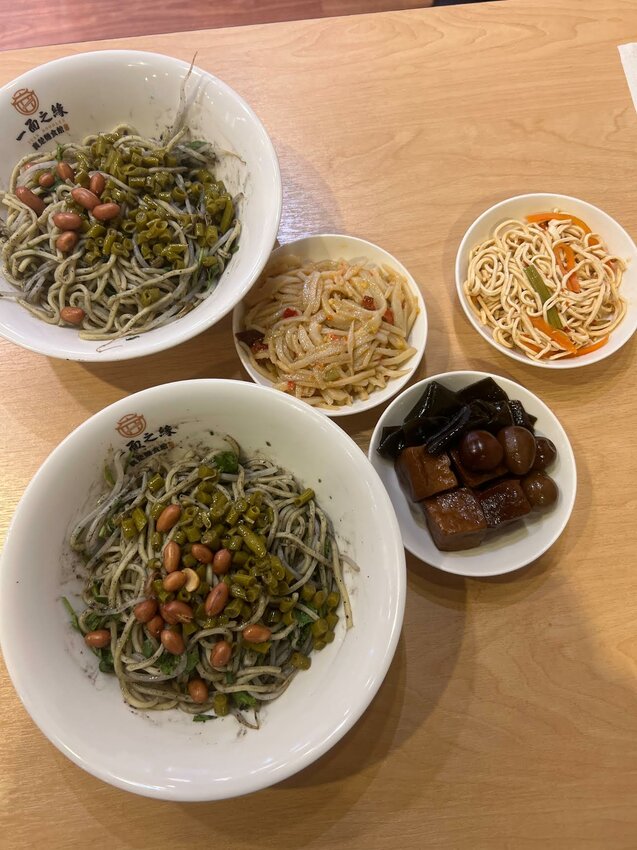 Asian-style squid ink noodles and side dishes at a Taiwanese restaurant.