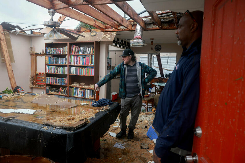 FORT MYERS, FLORIDA - OCTOBER 09: Connor Ferran (L) and his neighbor Leroy Roker survey what is left after what appeared to be a tornado tore the roof off of Ferran's home before Hurricane Milton's arrival on October 09, 2024, in Fort Myers, Florida. He said he had just had the roof replaced two years after Hurricane Ian had damaged it. People are preparing for the storm, which could be a Cat 3 when it makes landfall on Wednesday evening. (Photo by Joe Raedle/Getty Images)