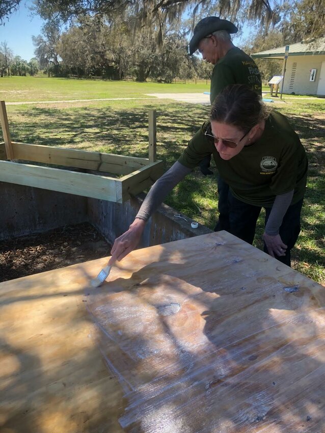 Heather, a volunteer, works to waterproof some of the outdoor pieces for the town of Ethel.