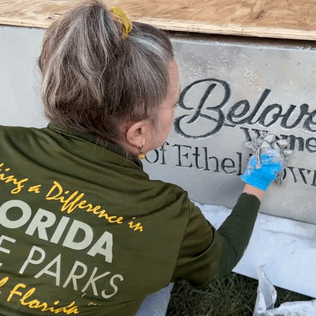 Kelly, volunteering on the Ethel project, adds a faux finish to the front of the monument at the entrance to the park.