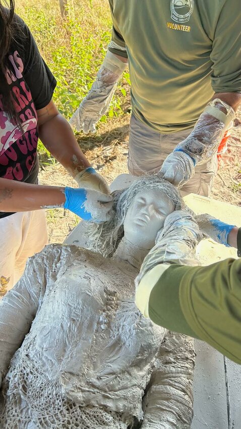 Volunteers work together to create the "statue" that represents all the "Beloved women of Ethel Township." It was a team effort. The dress used is an historic artifact donated to the park for this purpose.