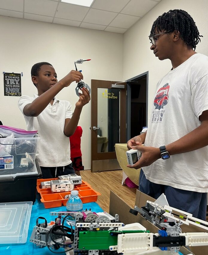 Instructor Johnathan Daly (right) assists a student with robotics.