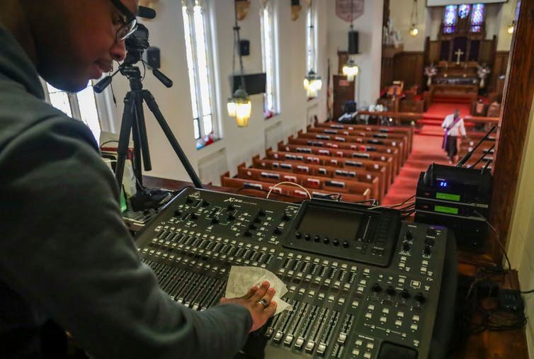 A multimedia technician wipes down audio equipment at a church in Brooklyn. AP Photo/Bebeto Matthews