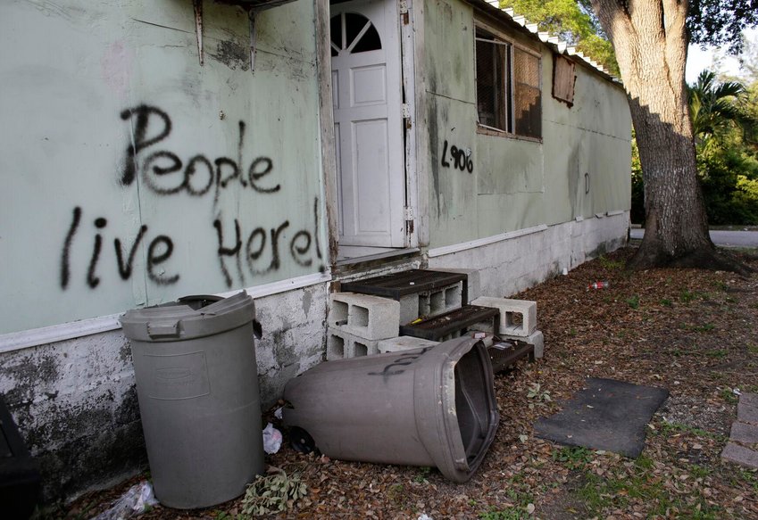 In this Monday, June 13, 2016 photo, graffiti is written on the side of a mobile home at the Little Farm trailer park in El Portal, Fla. In a city known for its glitzy, luxurious condo towers, affordable rental housing is hard to come by. Residents, many of whom had owned their mobile homes in this close-knit community for years, were evicted in July after the park was purchased in 2015 by Wealthy Delight LLC. The site is now in preliminary planning for mixed use development; AP Photo/Lynne Sladky