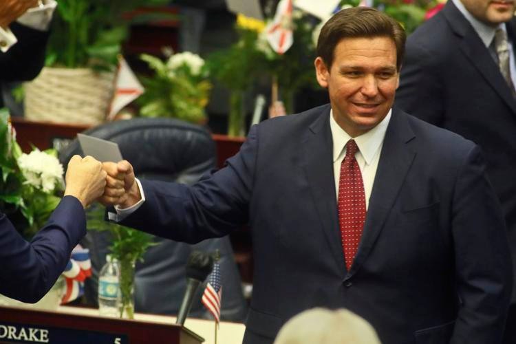 In this Tuesday, March 1, 2021 file photo, Florida Gov. Ron DeSantis fist bumps with legislators as he enters the House of Representatives prior to his State of the State address at the Capitol in Tallahassee, Fla. AP Photo/Phil Sears, File