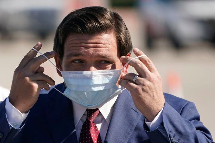 Gov. Ron DeSantis replaces his mask after speaking during a news conference at a COVID-19 testing site, Jan. 6, 2021; AP Photo/Wilfredo Lee