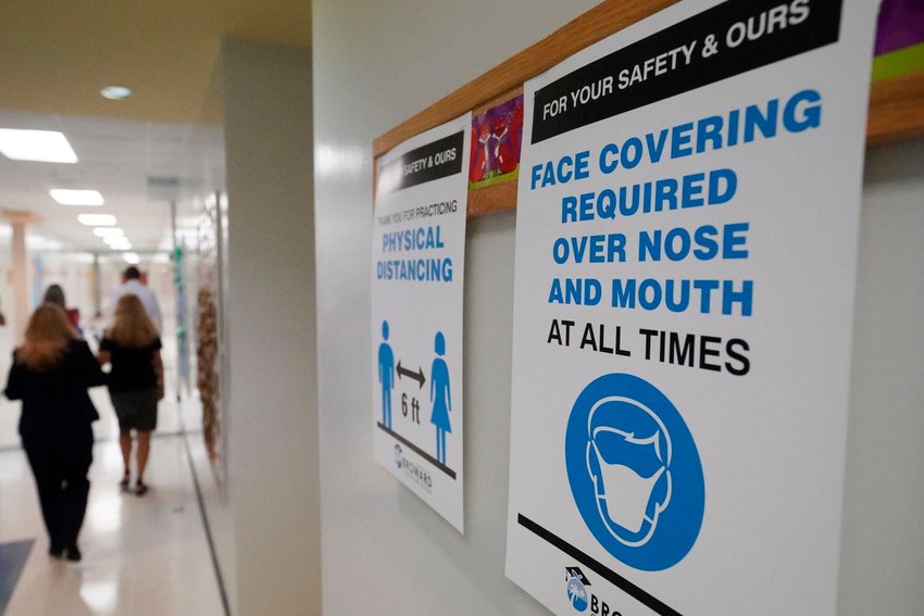 Signs in a hallway reminds students to wear masks and distance themselves at Fox Trail Elementary School, Friday, Oct. 9, 2020, in Davie, Fla. AP Photo/Wilfredo Lee