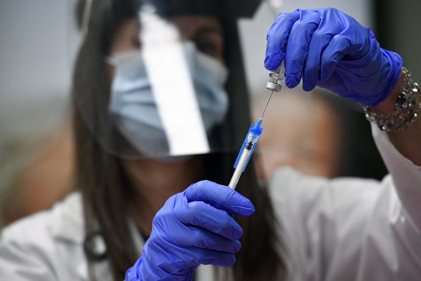 A clinical coordinator measures the exact dose of the COVID-19 vaccine before it is administered; Dec. 14, 2020. Credit: Helen H. Richardson/The Denver Post (pool)