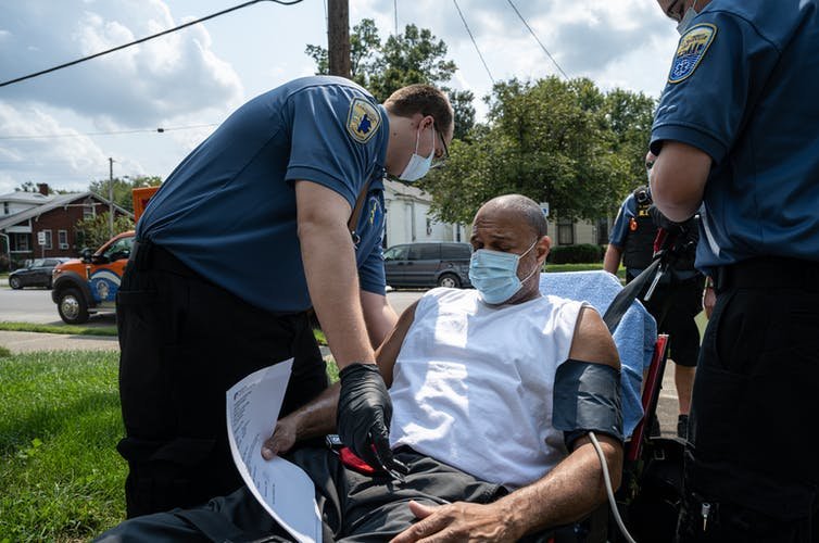 Emergency medical technicians aid a COVID-19 patient at his home in Louisville, Kentucky. Like much of the U.S., Louisville is experiencing an uptick in COVID-19 patients requiring emergency transport to medical facilities. John Cherry/Getty Images