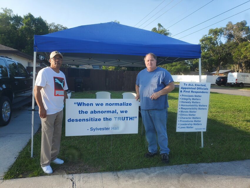 Leroy Bell and Dennis New standing beside a mobile location to receive completed and signed petitions.