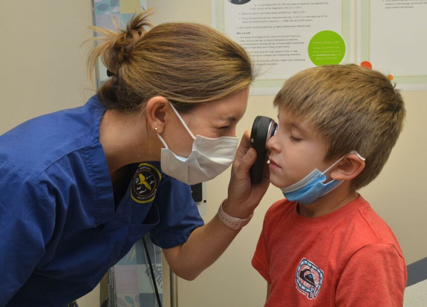 Lt. Cmdr. Kaitlyn Schiavone, a Navy dermatologist at Naval Hospital Jacksonville, conducts an exam with a 6-year-old.