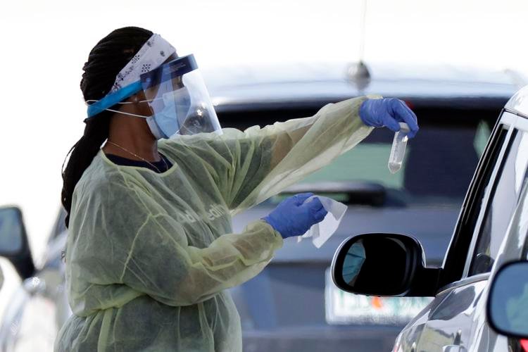 A health worker conducts COVID-19 tests at a drive-thru coronavirus testing site Tuesday, April 21, 2020, in Sanford, Fla. John Raoux / AP