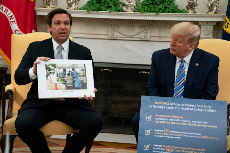 President Donald Trump (right) listens as Florida Gov. Ron DeSantis talks about the coronavirus response Tuesday, April 28, 2020, during a meeting in the Oval Office of the White House in Washington. Evan Vucci / AP