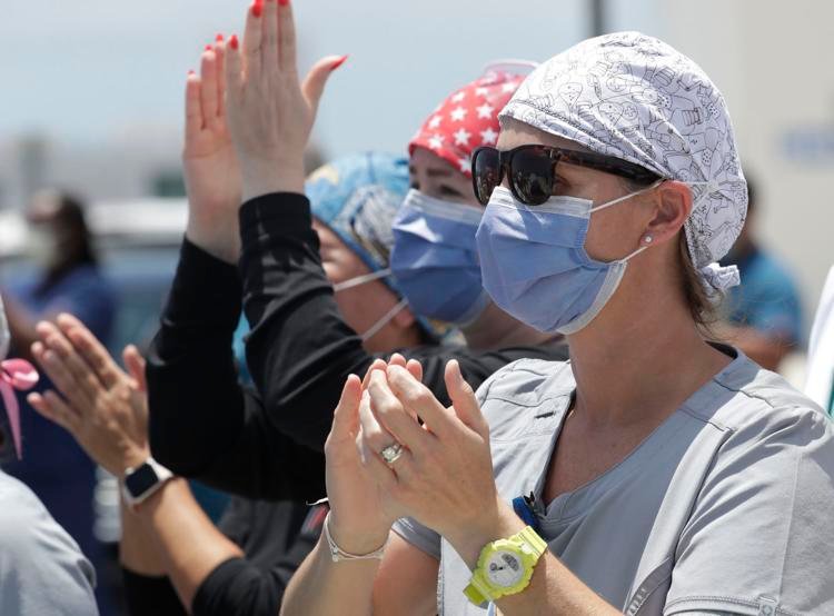 Healthcare workers from Jackson Memorial Hospital clap and cheer as they watch the U.S. Navy's Blue Angels flight demonstration squadron fly by, Friday, May 8, 2020, in Miami. The flyover was a salute to first responders in the wake of the coronavirus pandemic. Wilfredo Lee / AP