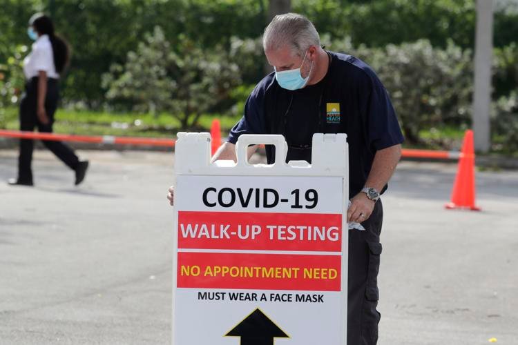An employee of the Florida Department of Health puts up a sign at a COVID-19 testing site at the West Perrine Health Center on Thursday, May 28, 2020, in Miami. The walk-up site is a joint operation between the Florida Department of Health and Community Health of South Florida, Inc. Lynne Sladky / AP