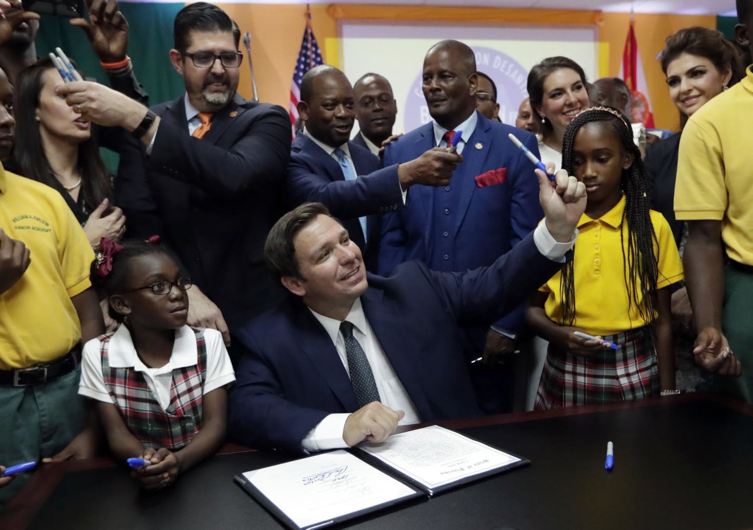 Florida Gov. Ron DeSantis, center, passes out pens used to sign a bill during a signing ceremony at the William J. Kirlew Junior Academy, Thursday, May 9, 2019, in Miami Gardens, Fla. The bill creates a new voucher program for thousands of students to attend private and religious schools using taxpayer dollars traditionally spent on public schools. At left is Sen. Manny Diaz, Jr.
Lynne Sladky / AP