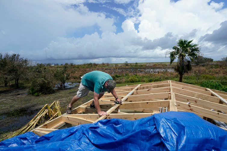 Mark Poindexter puts a tarp on the damaged roof of his home in Gulf Breeze, Louisiana, on Aug. 29, 2020, in the aftermath of Hurricane Laura.
AP Photo/Gerald Herbert