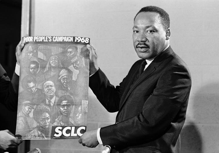 Dr. Martin Luther King Jr. displays the poster to be used during his Poor People’s Campaign in 1968.