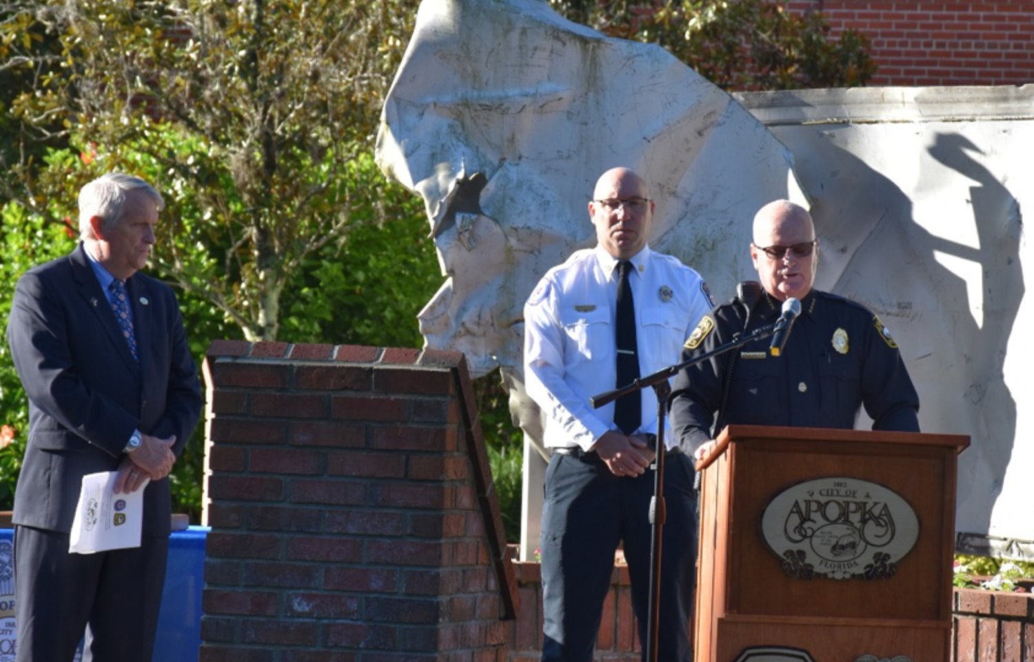 Apopka Police Chief Michael McKinley speaks during Apopka 9/11 ceremonies, with Mayor Bryan Nelson and Fire Chief Sean Wylam looking on.