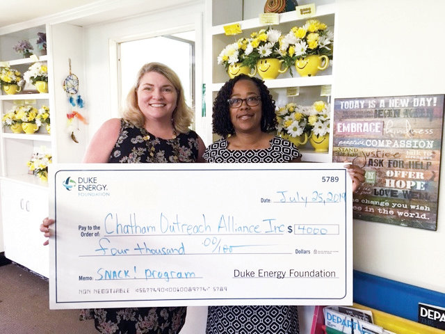 Melissa Driver Beard (left), CORA’s Executive Director, receives a check from Indira Everett, District Manager with Duke Energy, for a $4,000 grant for CORA's summer child meals program SMART!.