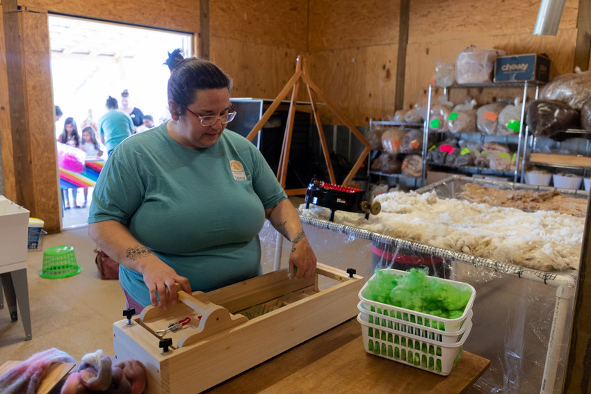 Laina Peck-Bostwick, farm manager of Carolina Sunshine Alpaca Farm, demonstrates for visitors how to turn sheared alpaca wool into yarn during the Farm's grand opening. Peck-Bostwick and her wife, Sarah, are longtime employees at the farm, having worked for its previous owners for a decade.