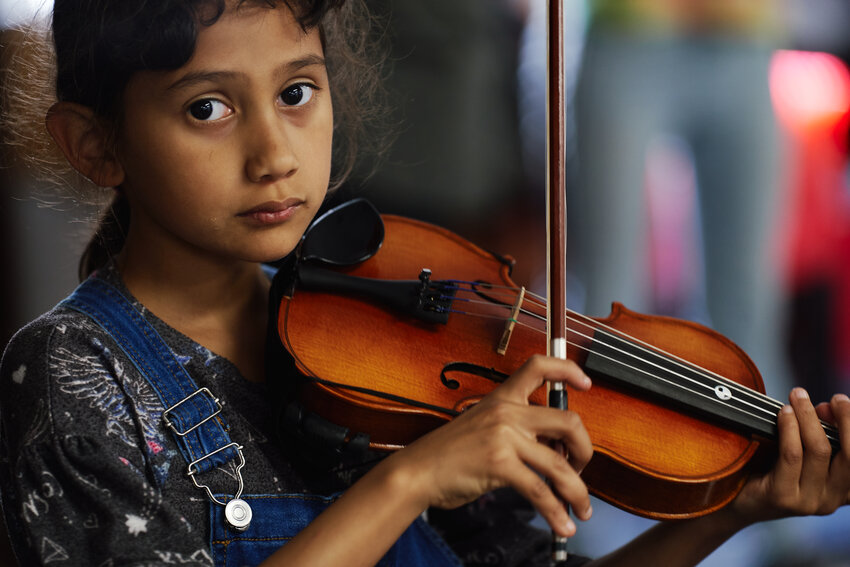 A student holds up their violin and bow at the after school strings program at Siler City Elementary School.