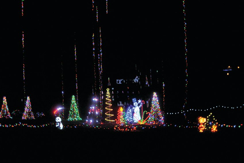 Straight lines of Christmas lights hang from the trees over the Johnson property, as festive trees, Snoopy, and Frosty the Snowman add the joy of Christmas to the Chatham County night.