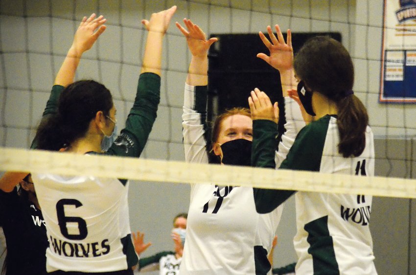 Woods Charter players Celine Keles (6), Jana Thompson (center) and Ada Green (11) celebrate a kill during a game in the Wolves' 3-0 sweep of Triangle Math and Science last Thursday. The victory extended the Wolves' winning streak to 11 games, with their last loss coming on Aug. 17.