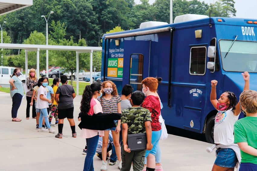 Students line up last July outside of the Bookmobile &mdash; a mobile library run by CCS's Siler City and Virginia Cross elementary schools to provide books to low-income students during the summer break from school.