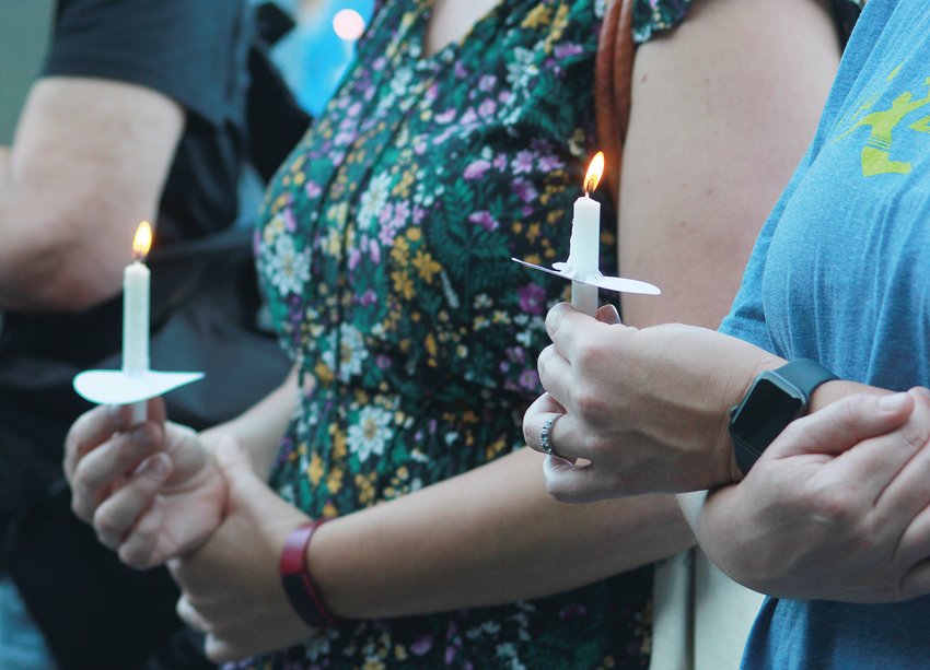 Participants of the Chatham County vigil for recent mass shootings help one another light their candles on Sunday in Pittsboro.
