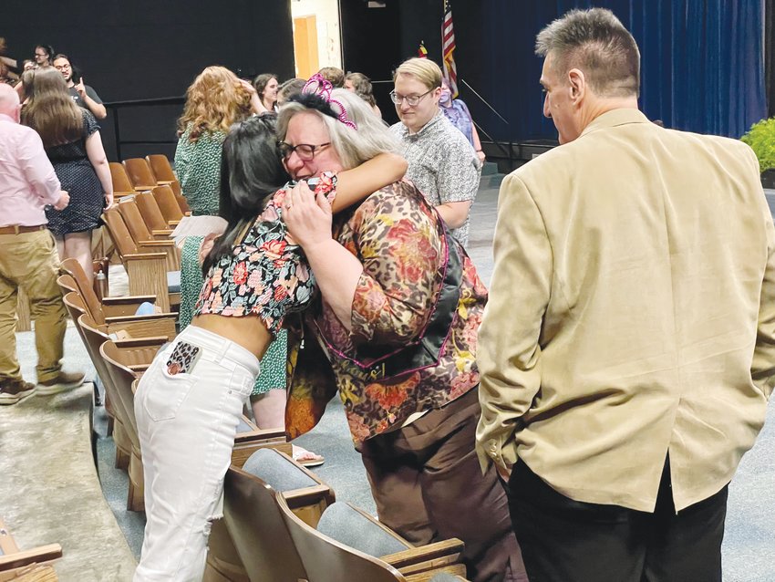 Retiring Jordan-Matthews High School Librarian Rose Pate hugs a former student after her retirement ceremony in the school's audiorium last Wednesday. Her husband, Chip, looks on.