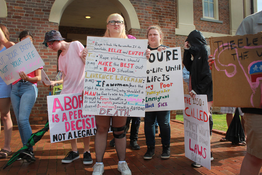 Protesters hold signs outside of the Pittsboro Historic Courthouse  during the abortion and women&rsquo;s rights protest on Monday in Pittsboro. Dozens of people gathered at the courthouse as a reaction to the overturning of Roe v. Wade.