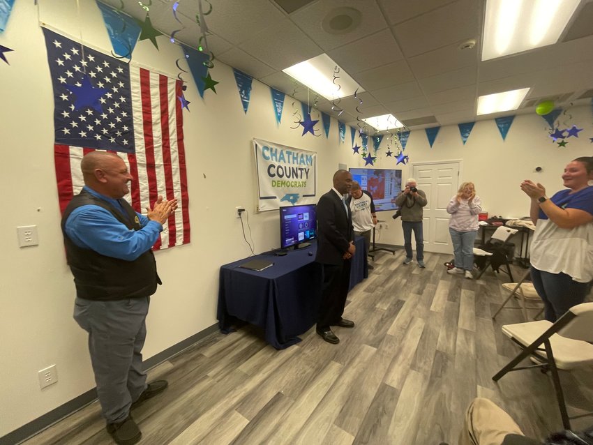 Sheriff Mike Roberson (left) and Rep. Robert Reives II (center) celebrate victories in their elections on Tuesday night at the Chatham Democrats office in Pittsboro.