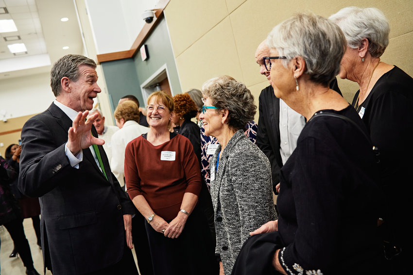 N.C. Gov. Roy Cooper visited Chatham County last Thursday, attending a Democratic Party event in Pittsboro at the invitation of Rep. Robert Reives II. Cooper, shown speaking with some attendees at the event, helped honor county volunteers and donors. &lsquo;Our officer team is deeply indebted to Robert Reives&rsquo; campaign for making our event so incredibly successful,&rsquo; said Liz Guinan, who&rsquo;s stepping down from the local party&rsquo;s chairperson position. &lsquo;Robert&rsquo;s generous spirit is on display to all of us in Chatham County, as witnessed by his devotion to bringing manufacturing jobs to Chatham, his work in addressing Pittsboro&rsquo;s water issues, his cooperation in negotiating a state budget, and a host of issues he fights for every day. Robert consistently works to improve lives in Chatham County, regardless of party affiliation. We cannot thank him enough.&rsquo; Cooper, Reives. Sen. Natalie Murdock and others spoke at the event, held at the Chatham County Agriculture &amp; Conference Center.