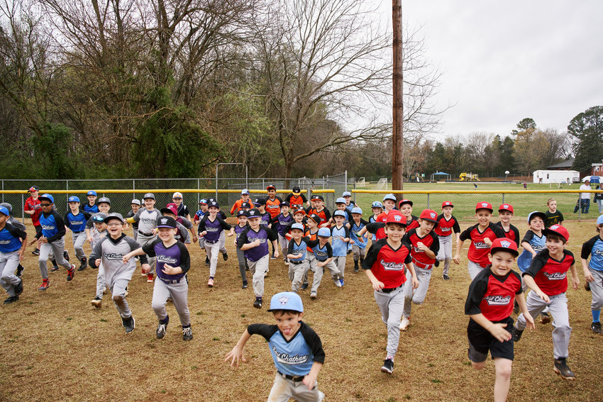 Players from East Chatham Little League rush the field for opening day in Pittsboro on Saturday.