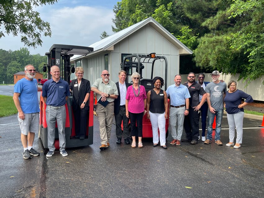 Individuals who had a hand in bringing the Central Carolina Community College Building Bridges Program gather to watch the most recent cohort maneuver the donated forklifts on Wednesday, July 19.