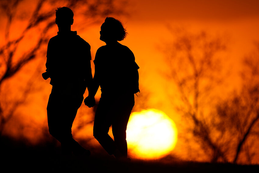 A couple walks through a park at sunset, March 10, 2021, in Kansas City, Mo. U.S. life expectancy rose in 2022 by more than a year. (AP Photo/Charlie Riedel, File)