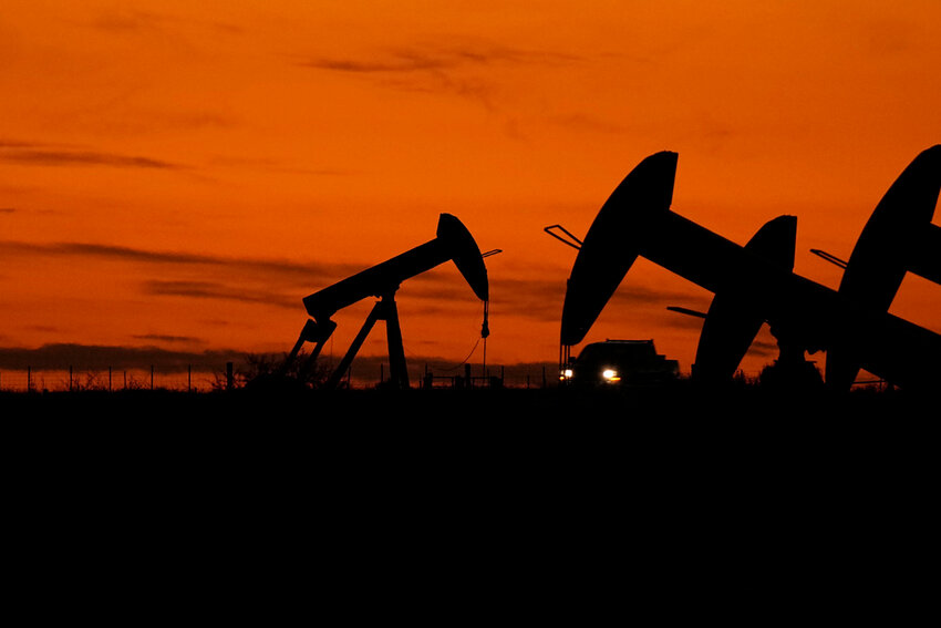 A truck passes oil pump jacks at dusk near Karnes City, Texas, Nov. 1, 2023. (AP Photo/Eric Gay, File)