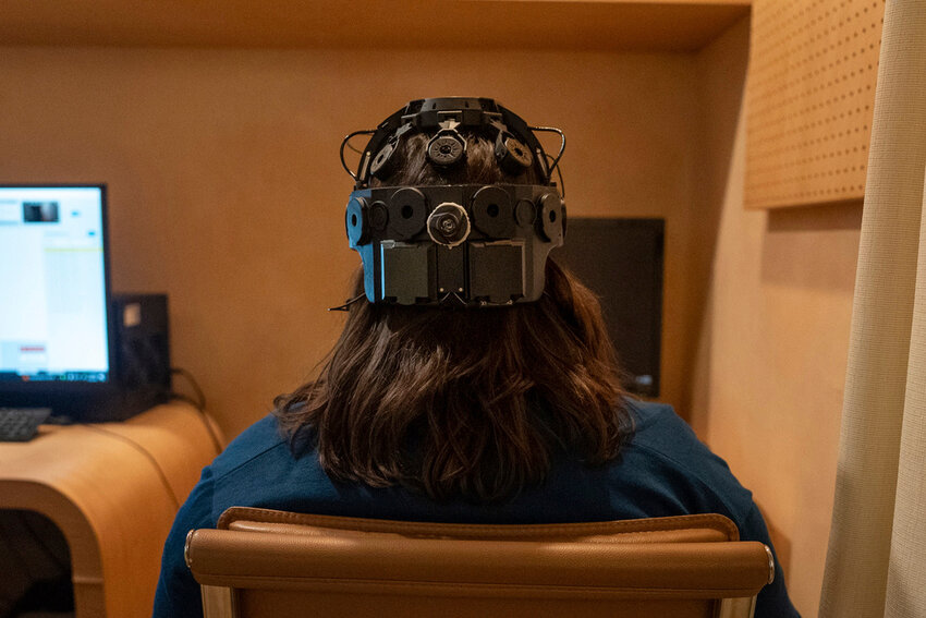 Emily Hollenbeck, a deep brain stimulation therapy patient, demonstrates an EEG device that records brain activity as she reacts to short videos at Mount Sinai’s “Q-Lab” in New York on Dec. 20, 2023. (AP Photo/Mary Conlon)