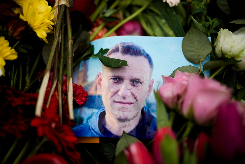 Rain drops cover a portrait of Russian opposition leader Alexei Navalny, placing between flowers in front of the Russian embassy in Berlin, Wednesday, Feb. 21, 2024. (AP Photo/Markus Schreiber)