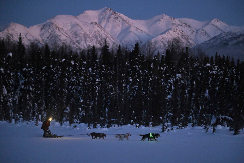 Musher Dutch Johnson, a kennel manager at The August Foundation for Alaska Racing Dogs, runs a dog team on Dee Lake in Chugiak, Alaska, Jan. 23, 2024. The lead dogs are illuminated for safety. Alaska’s wild spaces are getting more crowded and dangerous for Alaska’s four-legged athletes training for the Iditarod, an annual sled dog race that celebrates the official state sport. (Bill Roth/Anchorage Daily News via AP)