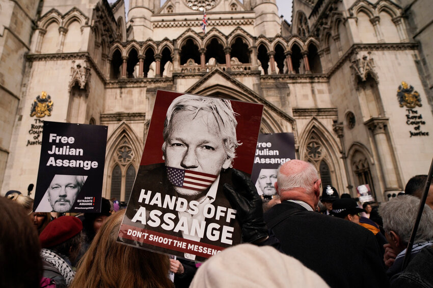 Demonstrators hold placards after Stella Assange, wife of Wikileaks founder Julian Assange, released a statement outside the Royal Courts of Justice, in London, Tuesday, March 26, 2024. (AP Photo/Alberto Pezzali)