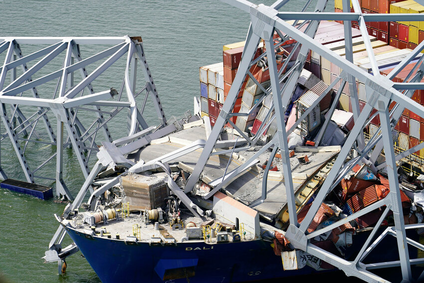 The cargo ship Dali lies under part of the structure of the Francis Scott Key Bridge after the ship hit the bridge, Tuesday, March 26, 2024, in Baltimore. (Maryland National Guard via AP)