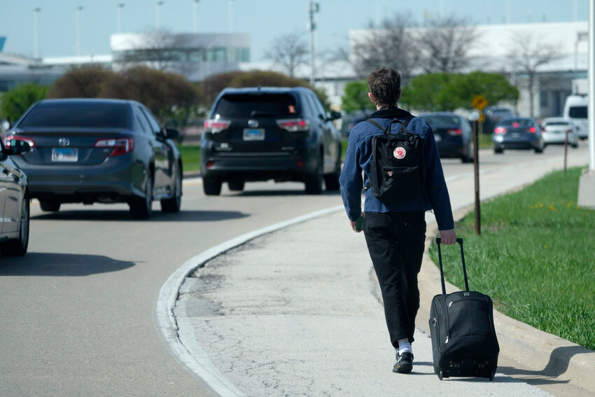 A passenger walks on the highway with his luggage at O'Hare International Airport in Chicago, Monday, April 15, 2024. (AP Photo/Nam Y. Huh)