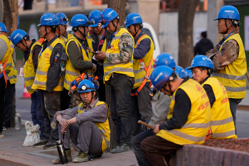 Workers wait for transport outside a construction site in Beijing, Tuesday, April 9, 2024. (AP Photo/Ng Han Guan)