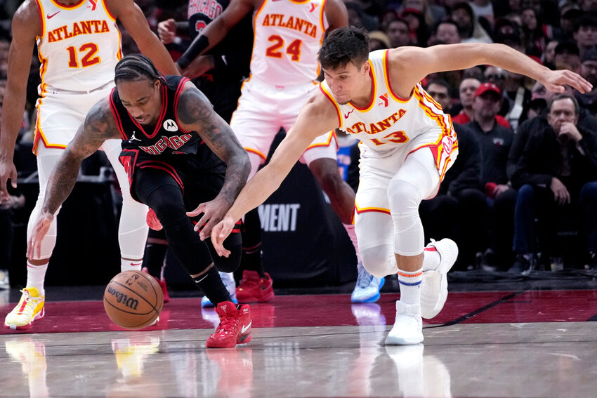 Chicago Bulls forward DeMar DeRozan, left, and Atlanta Hawks guard Bogdan Bogdanovic reach for the ball during the first half of an NBA play-in tournament game in Chicago, Wednesday, April 17, 2024. (AP Photo/Nam Y. Huh)