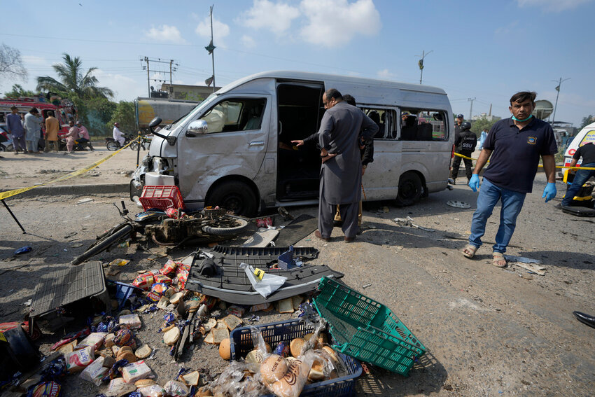 Pakistani investigators examine a damaged van at the site of a suicide attack in Karachi, Pakistan, Friday, April 19, 2024. (AP Photo/Fareed Khan)