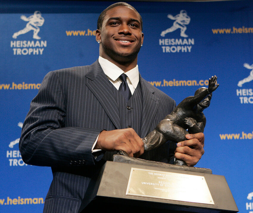 Heisman Trophy winner Reggie Bush of the University of Southern California smiles while posing for photos after a news conference in New York, Dec. 10, 2005. (AP Photo/Frank Franklin II, File)